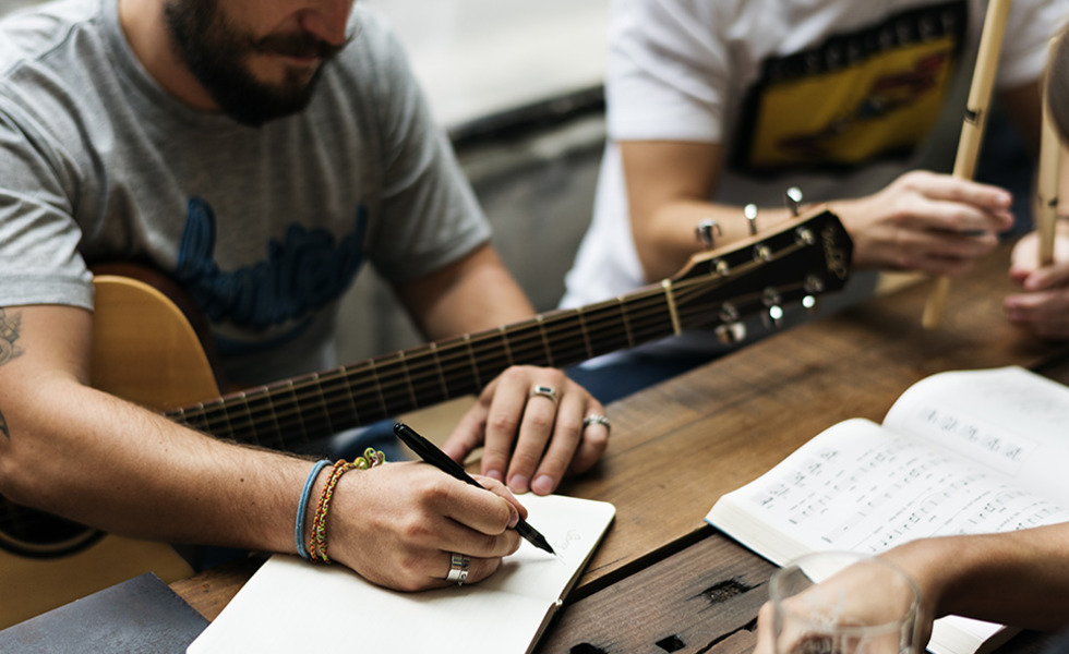 Gitarrist sitzt am Stich und schreibt einen Song